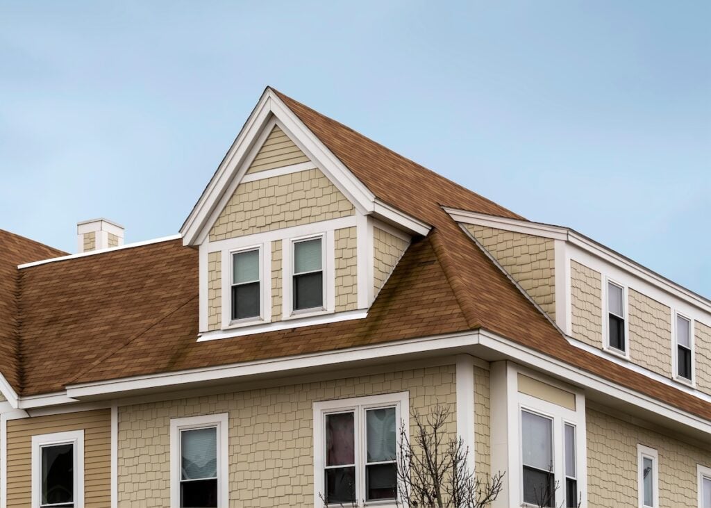 Dormer windows on the sloped shingle roof of a newly built house