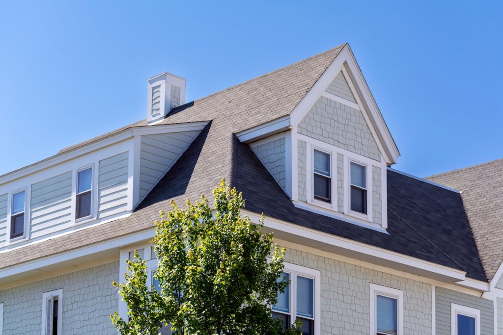 Dormer windows on the sloped shingle roof of a newly built house