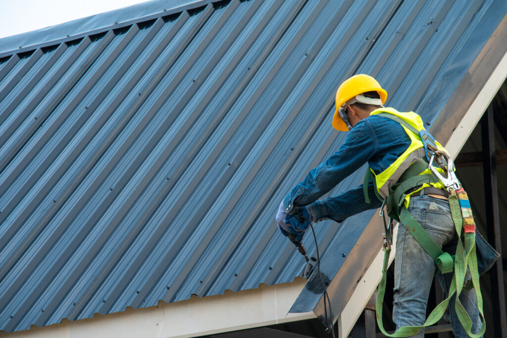 questions to ask a roofer Construction worker wearing safety harness belt during working on roof structure of building on construction site,Roofer using air or pneumatic nail gun and installing metal roof tile on top new roof.