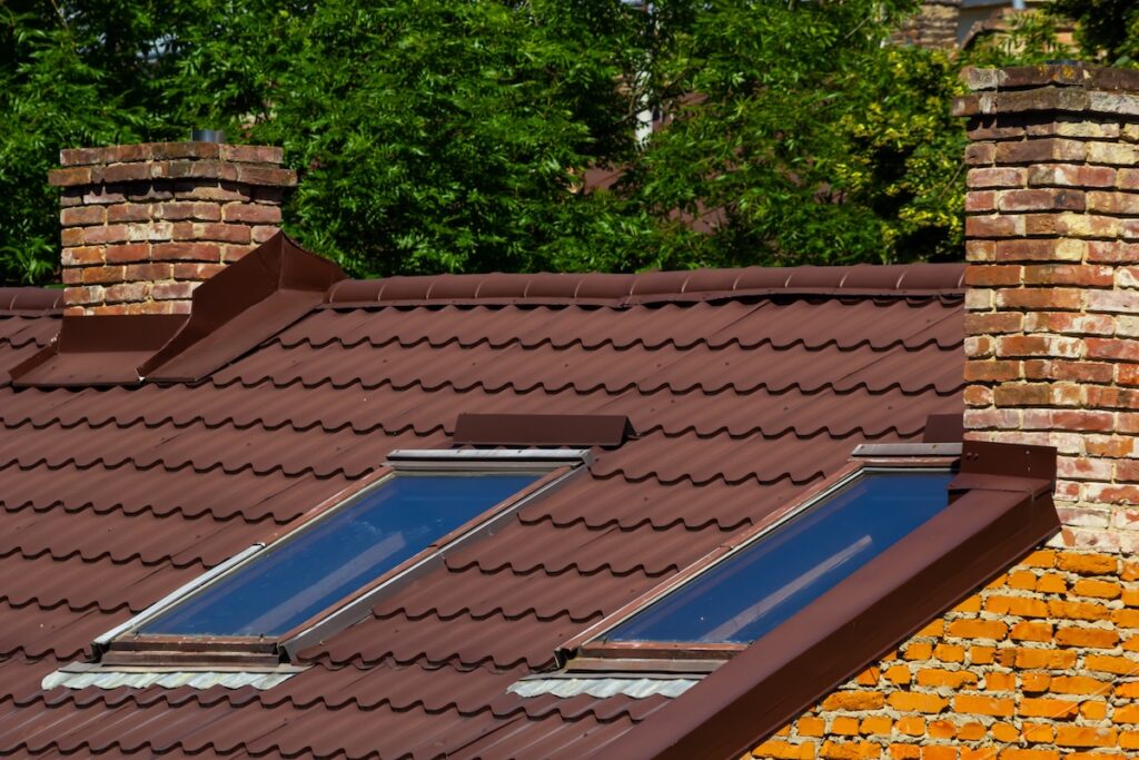 roof flashing types Red house roof with red brick chimney. Ceramic chimney, metal roof tiles, gutters.