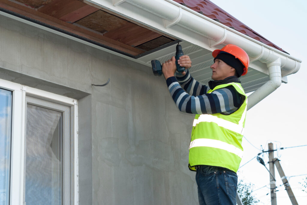 bad roofing contractors construction worker mounts a soffit on the roof eaves