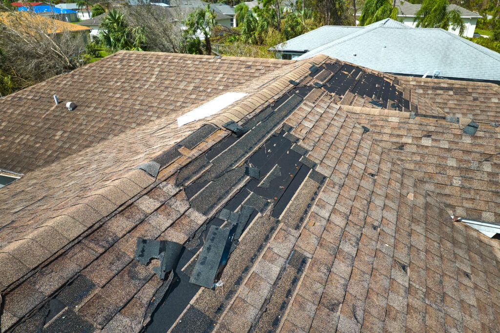 how to find a roof leak Damaged house roof with missing shingles after hurricane Ian in Florida. Consequences of natural disaster.